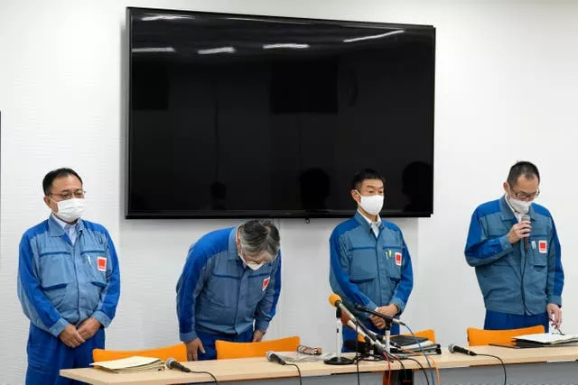 Tokyo Electric Power Company Holdings executive Junichi Matsumoto, second left, who is in charge of the treated water release from the Fukushima Daiichi nuclear power plant, bows at the beginning of a regular press conference in the Okuma town on the north-eastern coast of Japan