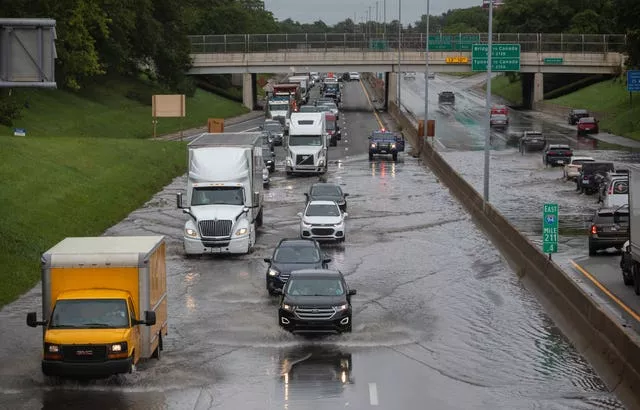 Dozens of vehicles drive through a flooded road in Detroit