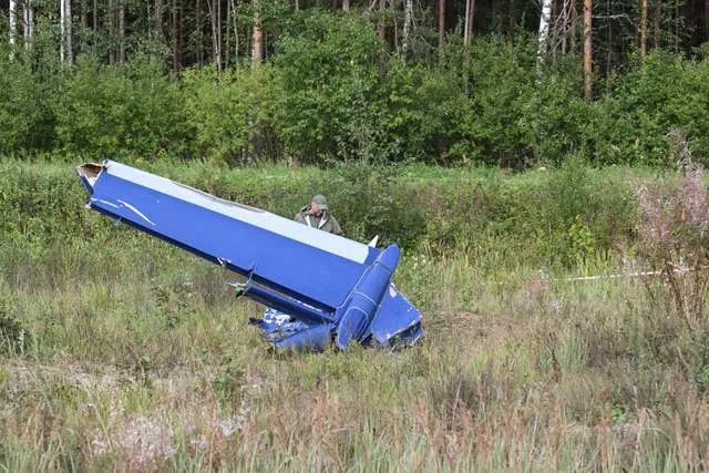 A Russian serviceman inspects part of a crashed private jet near the village of Kuzhenkino, Tver region, Russia