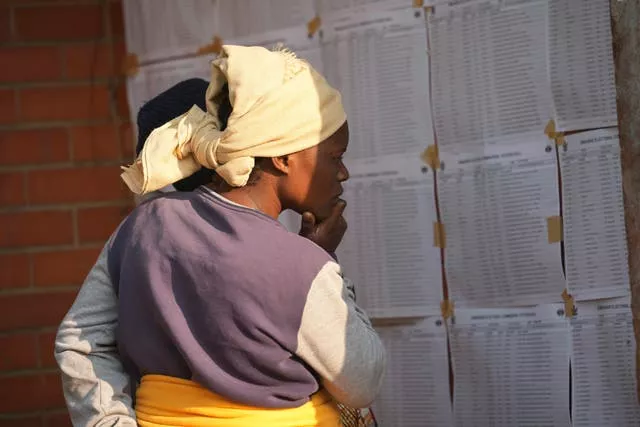 A woman looks for her name, outside a polling station in Harare