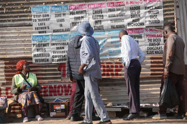 Pessoas lêem manchetes de jornais nas ruas de Harare