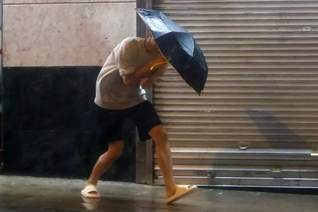Um homem com um guarda-chuva luta contra fortes ventos e chuva em Hong Kong