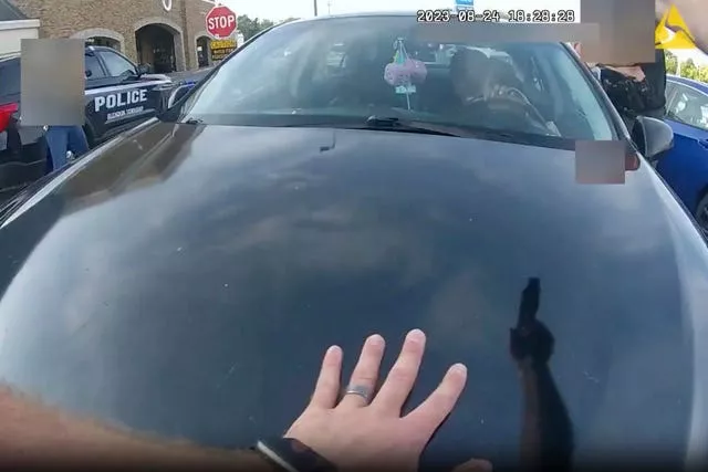 An officer pointing his gun at Ta’Kiya Young moments before shooting her through the windshield