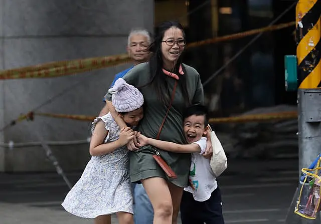 People struggle to walk against gusts of wind in Taipei on Sunday