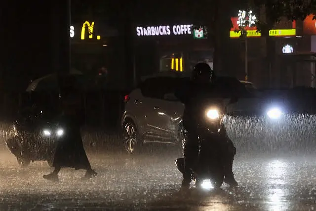 People walk and drive in heavy rain as Typhoon Haikui approached Taiwan on Saturday