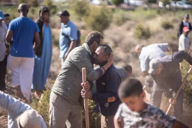 People comfort each other while digging graves for victims of the earthquake