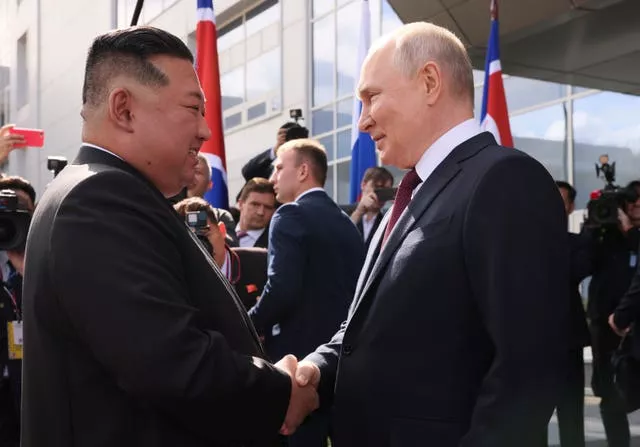 Vladimir Putin e Kim Jong Un apertam as mãos 