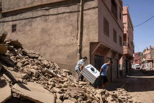 Personas recuperan una lavadora de su casa que fue destruida por el terremoto 