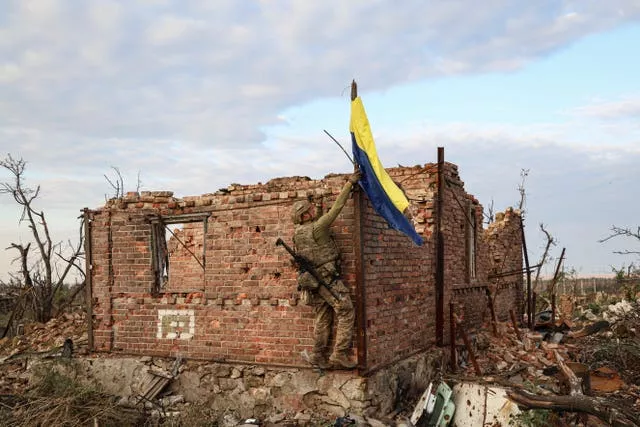 Um comandante da unidade de assalto da 3ª Brigada de Assalto levanta a bandeira ucraniana como símbolo de libertação da vila de Andriivka, na linha de frente, na região de Donetsk