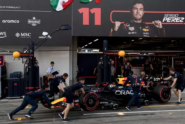 Red Bull mechanics push Sergio Perez's car back into the garage