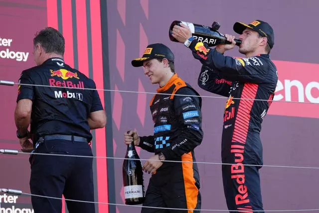 Max Verstappen, right, sips champagne on the podium alongside Red Bull boss Christian Horner, left, and McLaren's Oscar Piastri