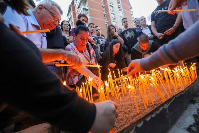Pessoas acendem velas para os três sérvios mortos na parte norte da cidade etnicamente dividida de Mitrovica, no Kosovo, dominada pelos sérvios.