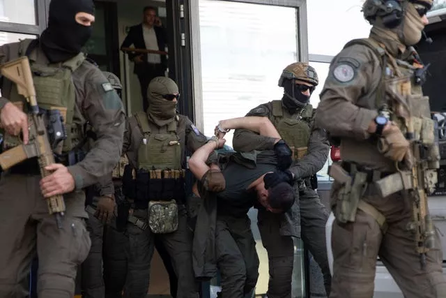 Policiais do Kosovo da Unidade de Intervenção Especial escoltam um dos homens armados sérvios presos para fora do tribunal 
