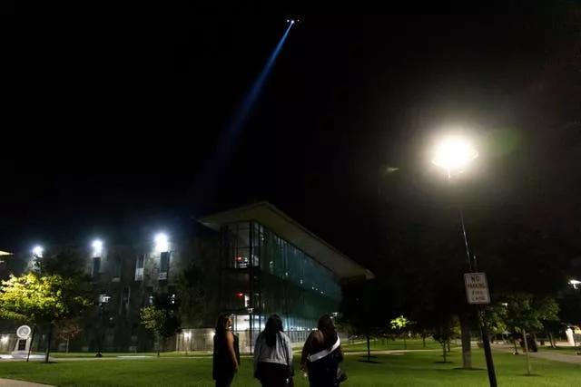 Estudantes assistem enquanto um helicóptero da polícia sobrevoa a Morgan State University após um tiroteio em Baltimore