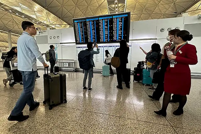 Travellers look at a flights information display