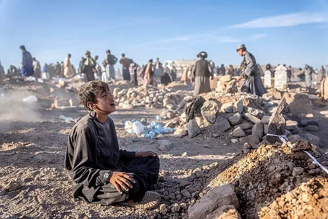 An Afghan boy mourns next to the grave of his brother 