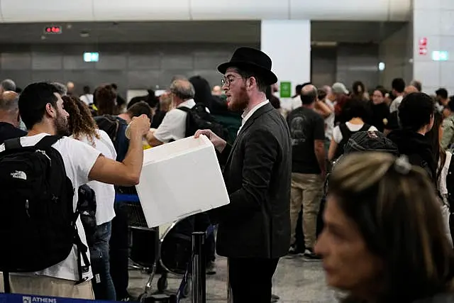 A man distributes sandwiches to passengers who are waiting in a queue to board flights to Israel at the Eleftherios Venizelos International Airport in Athens, Greece