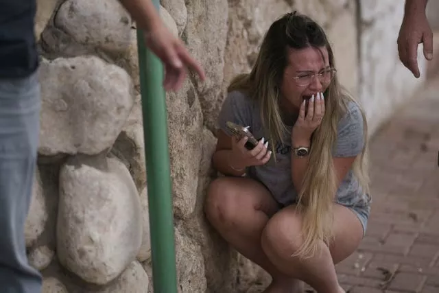 Uma mulher agacha-se, chorando, enquanto os israelenses se protegem dos disparos de foguetes vindos da Faixa de Gaza, em Ashkelon, sul de Israel, em 11 de outubro