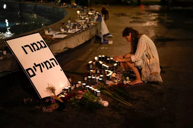 A woman lights candles in honour of victims of the Hamas attacks during a vigil in Tel Aviv, Israel 