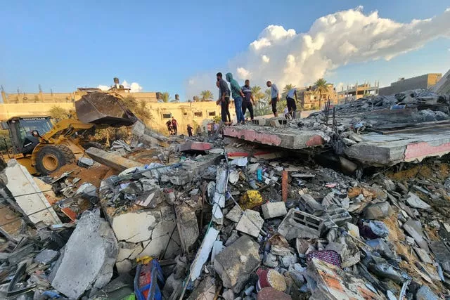 Palestinos estão entre os escombros de um prédio destruído por ataques aéreos israelenses em Deir el-Balah, Faixa de Gaza 