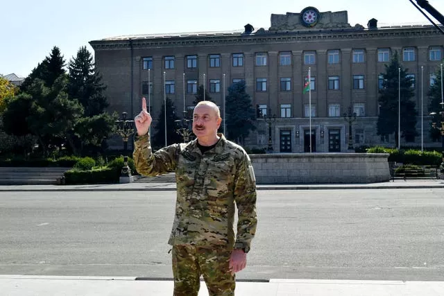 O presidente do Azerbaijão, Ilham Aliyev, fala em frente a um prédio do governo e a uma bandeira nacional do Azerbaijão na cidade de Khankendi 