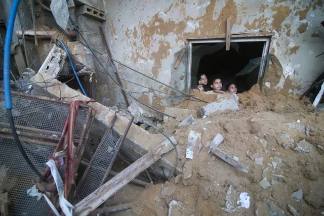 Palestinian children look at a building destroyed in Israeli airstrikes in Rafah 
