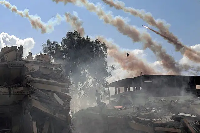 Rockets are fired from the Gaza Strip towards Israel over destroyed buildings following Israeli air strikes on Gaza City, central Gaza Strip