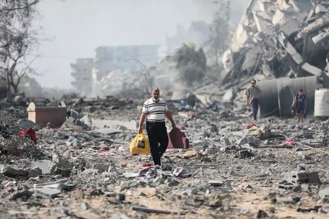 Palestinians walk past buildings destroyed in an Israeli bombardment 