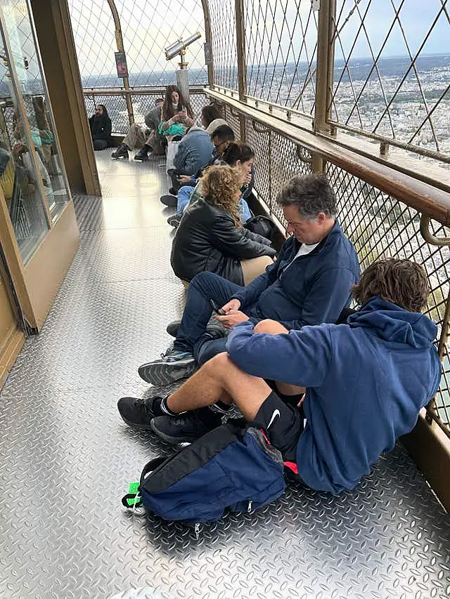 Visitors stranded at the top of the Eiffel Tower while police and firefighters dealt with a man climbing on the structure wait for the lifts to reopen in Paris