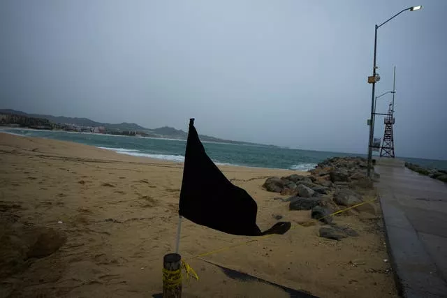 Uma bandeira negra balança ao vento, sinalizando uma praia fechada, em Cabo San Lucas, México
