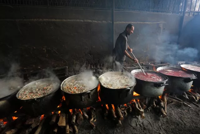 A Palestinian cooks food for people displaced in the ongoing Israeli bombardment of the Gaza Strip