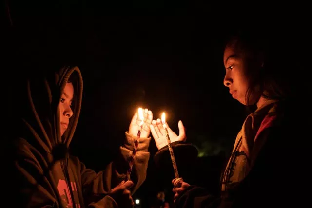 Youths hold candles over a tomb at a cemetery in Atzompa, Mexico, late on Tuesday