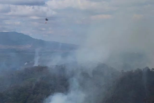Helicóptero joga água em incêndio florestal