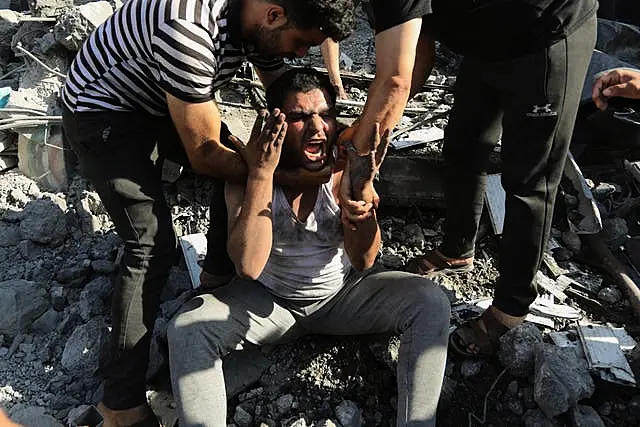 Palestinians comfort a crying man after he lost relatives under the rubble of a destroyed house following an Israeli airstrike in Gaza City on Saturday