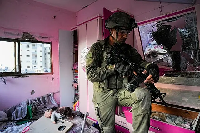 An Israeli soldier stands in an apartment during a ground operation in the Gaza Strip