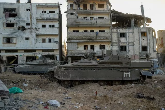 An Israeli armoured personnel carrier and a tank are seen next to destroyed buildings during a ground operation in the Gaza Strip on Wednesday