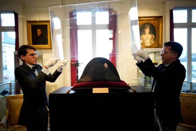 Raphael Pitchal, left, and Jean Christophe Chataignier of Osenat’s auction house remove the protection of one of the signature broad, black hats that Napoleon wore when he ruled 19th-century France and waged war in Europe at Osenat’s auction house in Fontainebleau, south of Paris