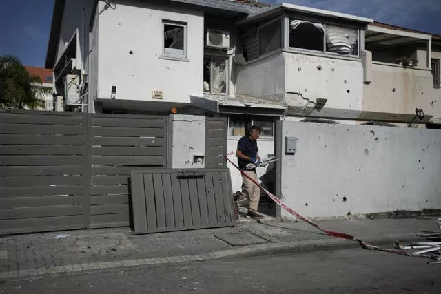 Pessoas inspecionam a casa danificada em Ashkelon, Israel, depois de ter sido atingida por um foguete disparado da Faixa de Gaza