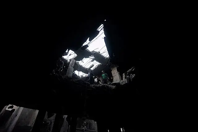 Palestinians look for survivors inside the remains of a destroyed building