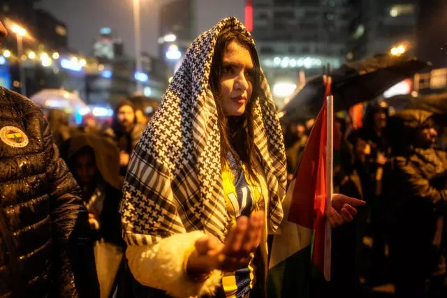 Uma mulher reza durante uma forte chuva durante um protesto pró-Palestina em frente ao consulado israelense em Istambul no sábado 