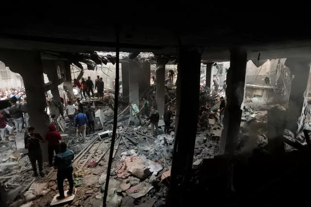 Palestinos procuram sobreviventes dentro dos restos de um prédio destruído após um ataque aéreo israelense no campo de refugiados de Khan Younis, no sul da Faixa de Gaza, no sábado