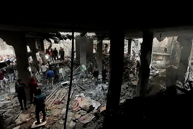 Palestinians look for survivors inside the remains of a destroyed building following an Israeli airstrike in Khan Younis refugee camp, southern Gaza Strip, on Saturday