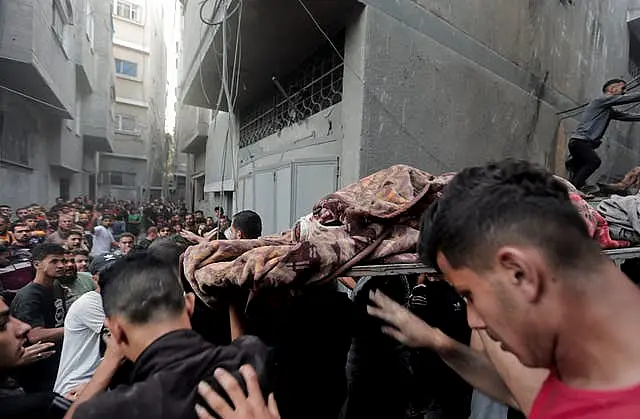 Palestinians evacuate an injured woman found under the rubble of a destroyed house after an Israeli airstrike in Khan Younis refugee camp, southern Gaza Strip, on Saturday 