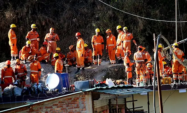 Rescuers rest at the site of the tunnel