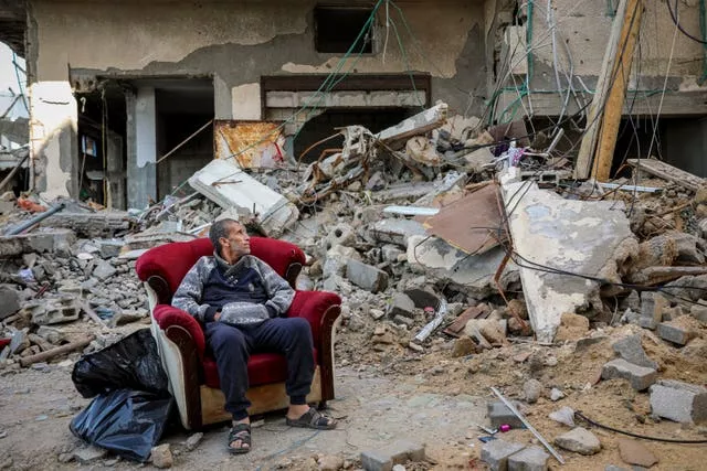 Um homem palestino sentado em uma poltrona do lado de fora de um prédio destruído na cidade de Gaza na quarta-feira 
