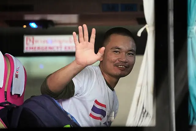 A Thai man freed after being taken hostage by Hamas waves from a bus after arriving at Suvarnabhumi International Airport