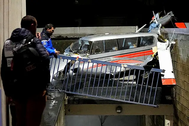 Police officers stand by a small plane that made an emergency landing in a residence in Villejuif, outside Paris