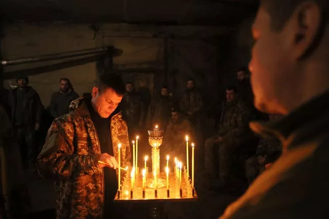 A Ukrainian serviceman of the 72nd mechanised brigade lights a candle during the sacred liturgy before the upcoming Christmas at the frontline near Vuhledar, Ukraine