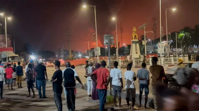 Moradores observam uma nuvem de fumaça de um depósito de petróleo em chamas em Conacri, Guiné, na segunda-feira