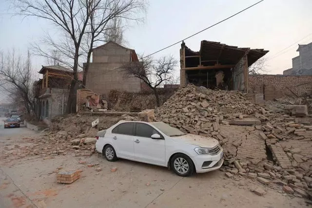 A vehicle is partially covered by a collapsed building in Dahejia